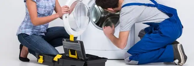 Washer repair technician inspecting a front-load washing machine with tools in Anaheim, CA