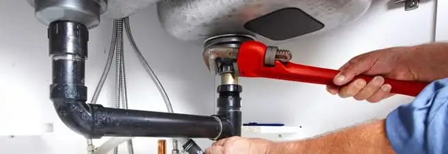 Garbage disposal repair technician tightening the sink drain and disposal connection in Anaheim, CA