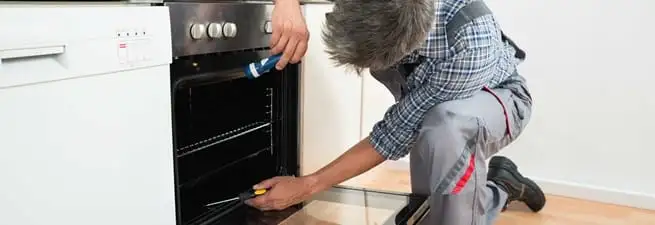 Oven repair technician inspecting and servicing an electric oven in Anaheim, CA