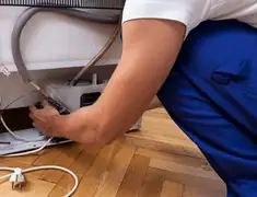 Appliance repair technician fixing refrigerator water line and connections in Anaheim, CA