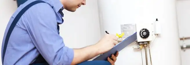 Water heater repair technician inspecting the unit and recording service notes in Anaheim, CA